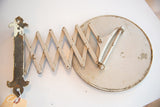 Antique shaving mirror's accordion arm, showing aged white paint and rust patina.