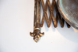 Rusted accordion mechanism and fleur de lis hardware with rich patina on antique mirror.