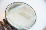 Aged shaving mirror surface with crackled silvering and dark, rusty accordion arm.