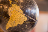 Yellow South America continent on vintage black Cram's globe, showing wear.