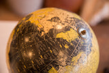 Vintage Cram's black globe showing the North Atlantic Ocean, Greenland, and aged yellow land.