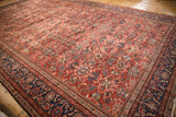 Vintage Mahal carpet's pale raspberry field and navy border with visible pile restoration.