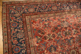 Cherry red field with palmette motifs and navy blue floral border of a vintage Mahal rug.