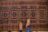 Geometric floral compartments, guls, and germinating plant border on an antique Belouch rug.