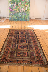 Antique Belouch rug section: geometric floral compartments, germinating plant border, madder root, navy.