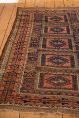 Detail of antique Belouch rug showing madder root geometric floral panels, navy guls, and visible foundation wear.
