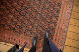 Antique Malayer rug's staggered fuschia raspberry boteh motifs on navy field with orange blush border.