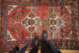 Vintage Hamadan rug with geometric double medallions, Herati motif, and worn cherry red pile.