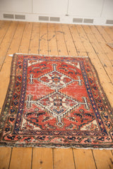 Geometric double medallion on a worn cherry red field of a vintage Hamadan rug.