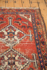Vintage Hamadan rug detail showing geometric stepped finials, cherry red field with wear, and navy blue border.
