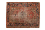 Antique Persian Heriz rug with worn diamond medallion, rust field, and navy samovar border.