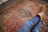 Antique Heriz rug displaying central diamond medallion, elongated finial, and time-softened rust field.