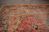 Antique Heriz rug’s worn rust field and navy samovar border, with visible foundation.