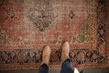 Antique Heriz rug's wide navy samovar border and rust field, revealing historic wear.