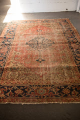 Antique Heriz rug's wide navy blue samovar border, with red and beige motifs and secured end.