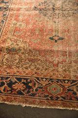 Worn navy and rust geometric border of an antique Heriz rug revealing foundation.
