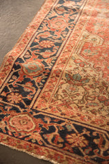 Antique Heriz rug's distinctive navy samovar border and rust field with age-softened hand-knotted pile.