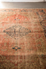 Antique Heriz rug's rust and navy motifs, showcasing wear across knot heads.