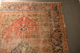 Antique Heriz rug corner, detailing navy, rust, beige patterned border and visible foundation wear.