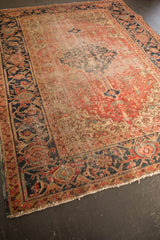 Worn corner of the antique Heriz rug with secured ends, showcasing the rust and navy samovar border.