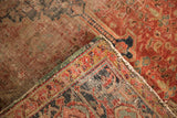 Corner of an antique hand knotted Heriz rug, showing worn pile and visible foundation.