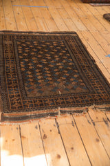Antique Belouch rug with tattered end, worn side, and brown, blue boteh motifs.