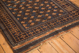 Antique Belouch rug's dark chocolate geometric border and tattered side with navy accents.