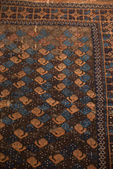Antique Belouch rug field detail: repeating blue and terracotta botehs, aged texture.