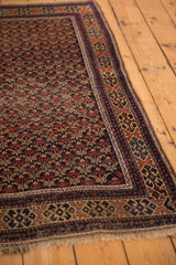 Antique Belouch rug corner with repeating trellis floral pattern, geometric border, and fringe.