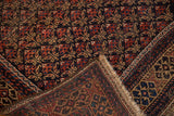 Hand-knotted antique Belouch rug showing worn pile, fringe, and navy and terra cotta trellis design.