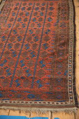 Antique Belouch rug: madder red, sky blue geometric columns, intact side border, and natural fringe.