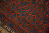 Antique Belouch rug’s geometric germinating floral pattern in madder red and sky blue, with fringe.