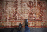 Intricate geometric motifs with heavy wear and threadbare sections on a Caucasian rug.