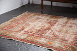 Antique Caucasian rug close-up: geometric animal motifs, threadbare areas, and rich chestnut, wine, ivory tones.