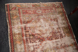 Antique Caucasian rug corner with geometric wine red border, frayed fringe, and threadbare pile.