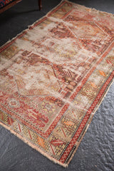 Antique Caucasian rug with significant threadbare wear, displaying geometric motifs in chestnut, red, and ivory.