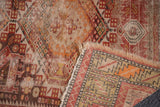 Antique Caucasian rug corner, threadbare pile, tattered fringe, and faded geometric motifs.
