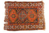 Vintage Caucasian rug, triple medallion hook motifs, orange, navy, ivory, low pile, tattered perimeter.