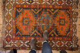 Geometric navy, tangerine, ivory patterns with worn pile and tattered fringe on this vintage Caucasian rug corner.