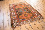 Tattered lower corner of the vintage Caucasian rug, showing geometric borders in ivory, orange, and blue.