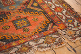 Tattered perimeter and surface wear on the vintage Caucasian rug's geometric hook motifs.