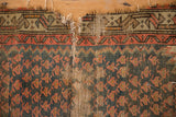 Antique Caucasian rug detail: prominent tear exposing foundation with worn tangerine boteh.