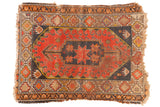 Vintage Caucasian rug, tomato red field, charcoal starburst medallion, geometric borders, storied wear.
