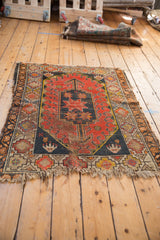 Geometric hook and starburst motifs on vintage Caucasian rug, with knot wear and tattered fringe.