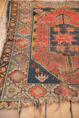 Tattered fringe and geometric border of a vintage Caucasian rug, showing worn pile.