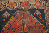 Caucasian rug detail: pronounced wear, exposed foundation, tattered fringe, geometric design.