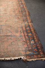 Antique Lilihan runner's tattered end and worn border with dusty raspberry, blue hues.