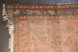Corner of an antique Lilihan runner, with tattered fringe, worn pile, and a pale raspberry, sky blue border.