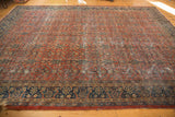 Vintage Mahal carpet's tattered fringe, patterned navy border, and worn madder root red field.