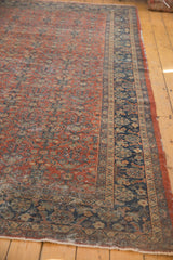Madder root red field, navy floral border, and tattered edge of a vintage Persian Mahal carpet.